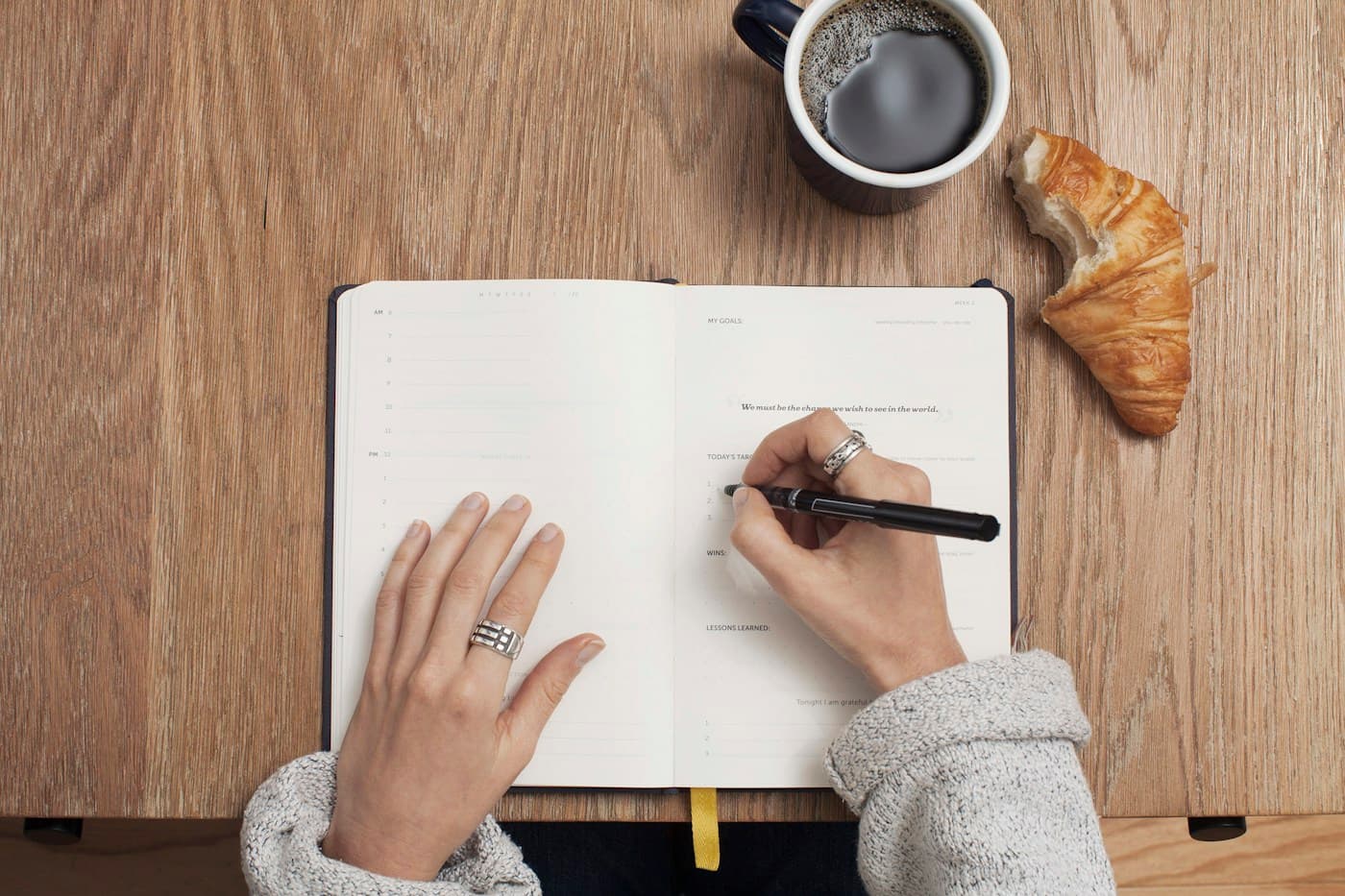 A person writing in a notebook at a cafe table